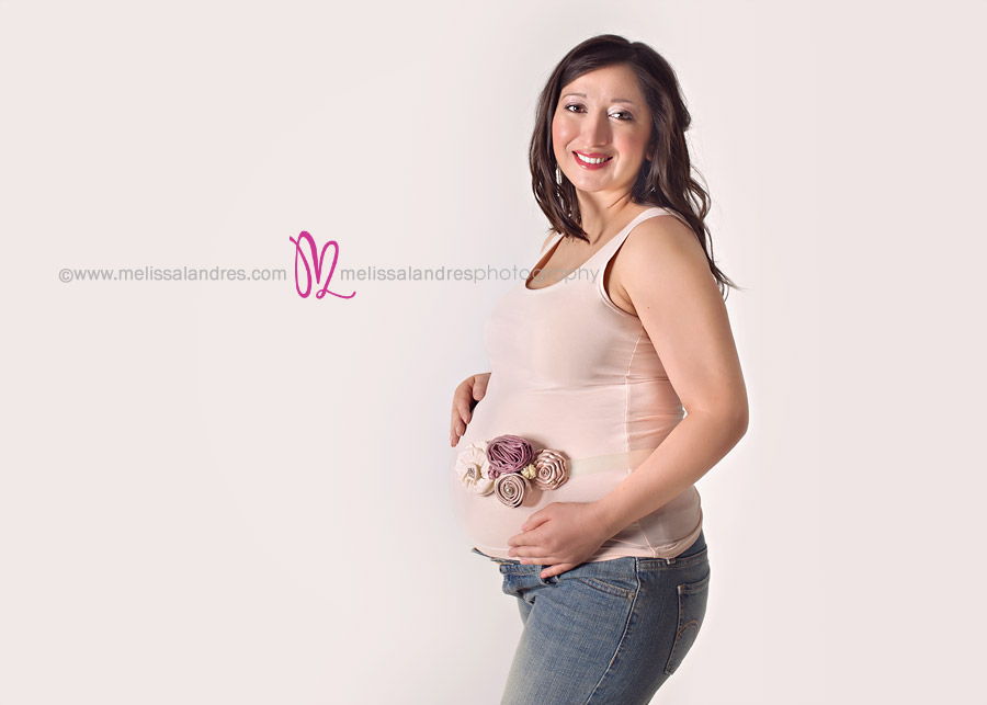 pregnant mother smiling, classic jeans and tank top portrait with pink maternity sash