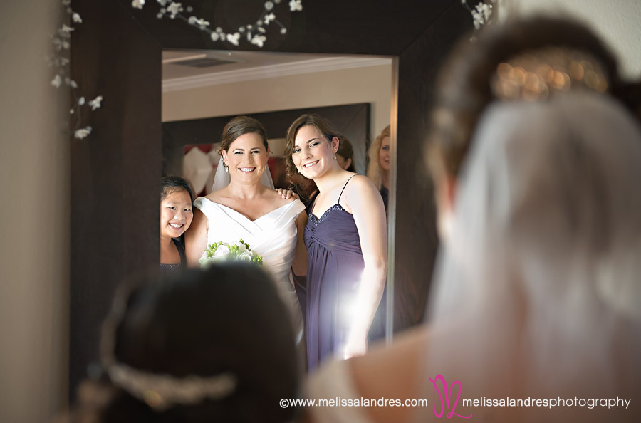 Bride and her family looking in the mirror together by wedding photographer Melissa Landres