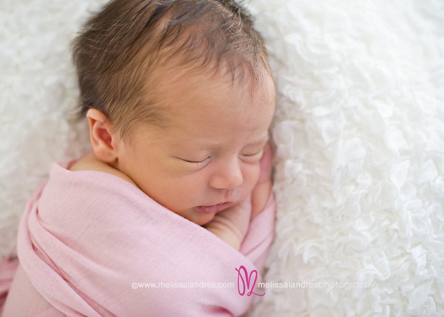 sleeping newborn baby girl with pink blanket on white lace