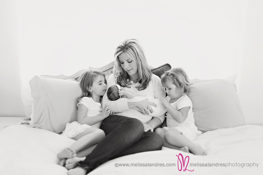 Mom with newborn baby and daughters snuggling on the bed, black and white photos