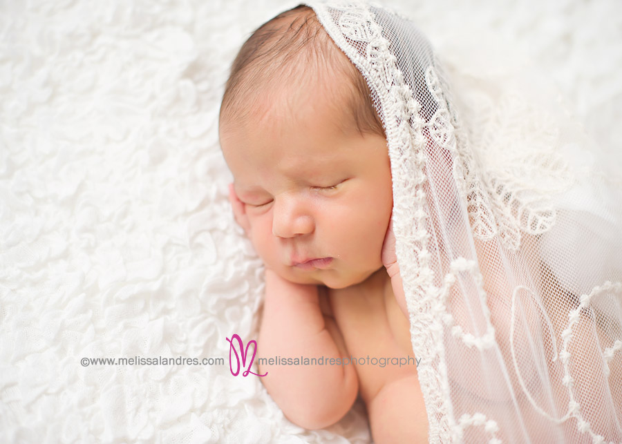 newborn baby girl sleeping on white blanket wrapped in vintage lace