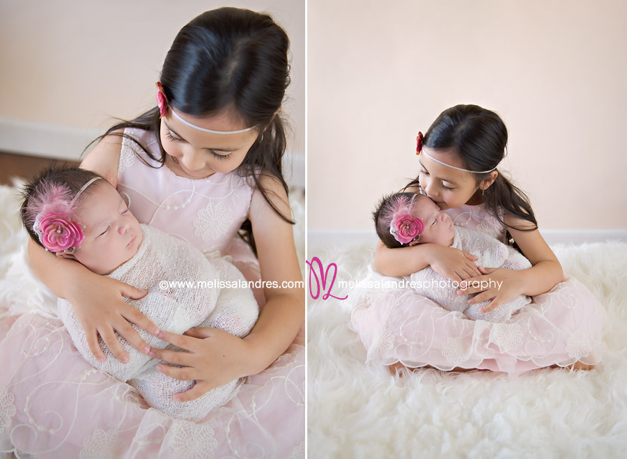 newborn baby girl held by her loving big sister