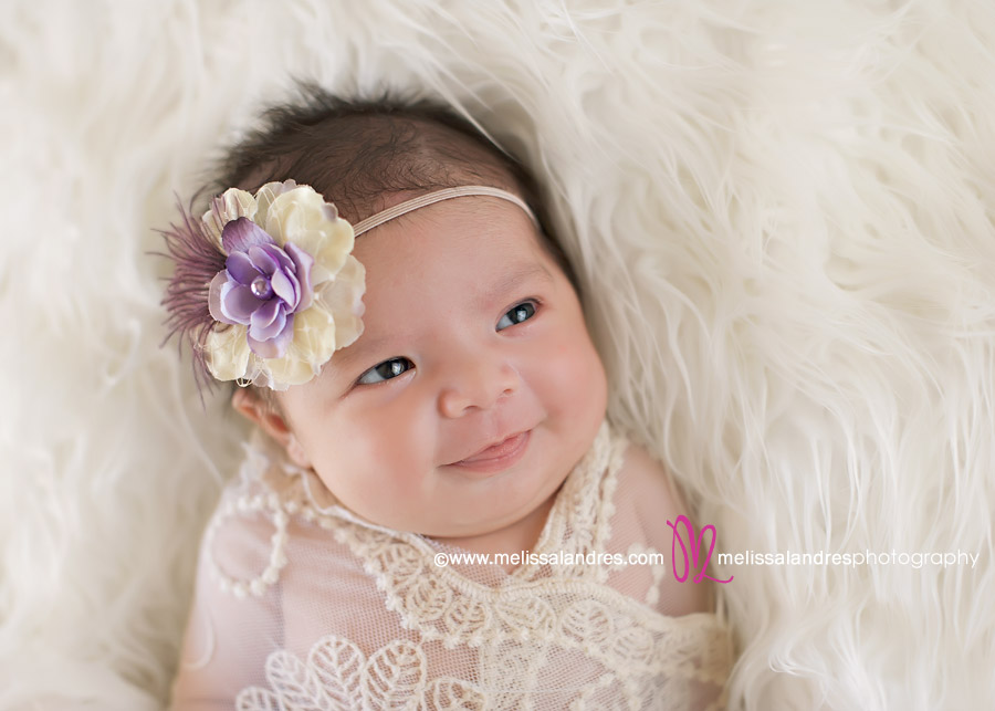 newborn baby girl wrapped in lace on white fur rug