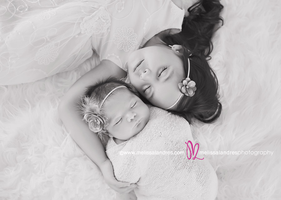 beautiful black and white portrait of a newborn baby girl and her sister