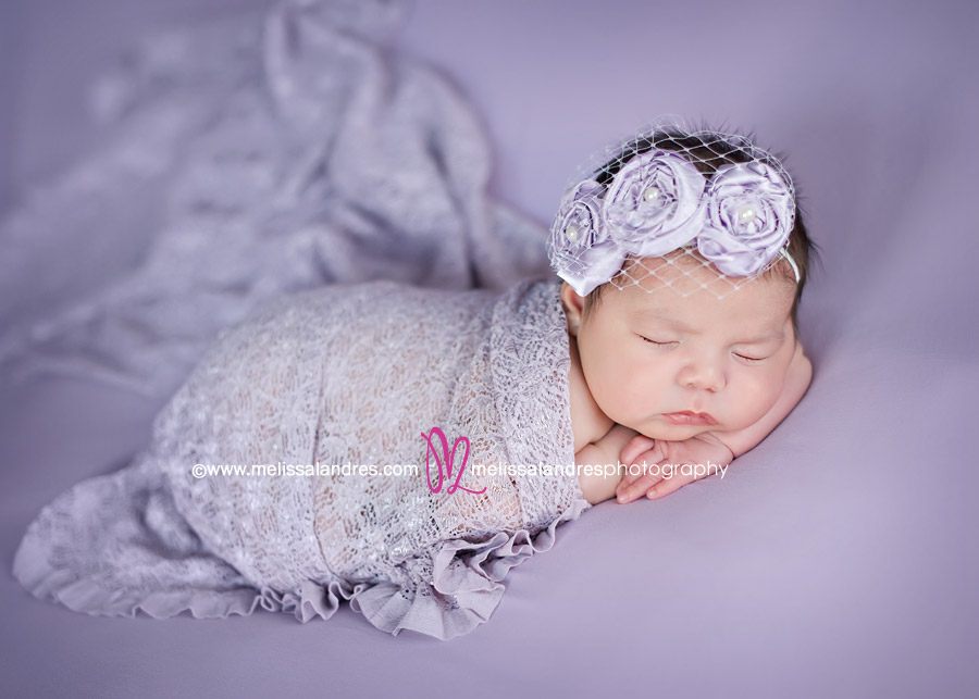 beautiful newborn baby girl with lavender hairband and pretty lace wrap