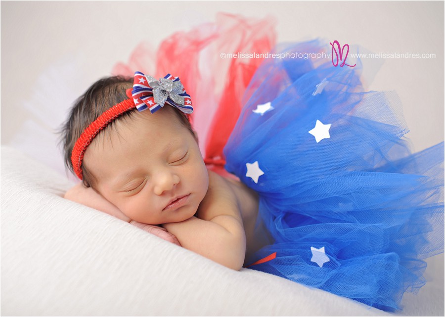 newborn baby girl in fun red, white, and blue tutu for first photos