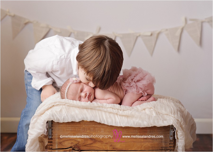 toddler kissing his brand new sleeping little sister for photos