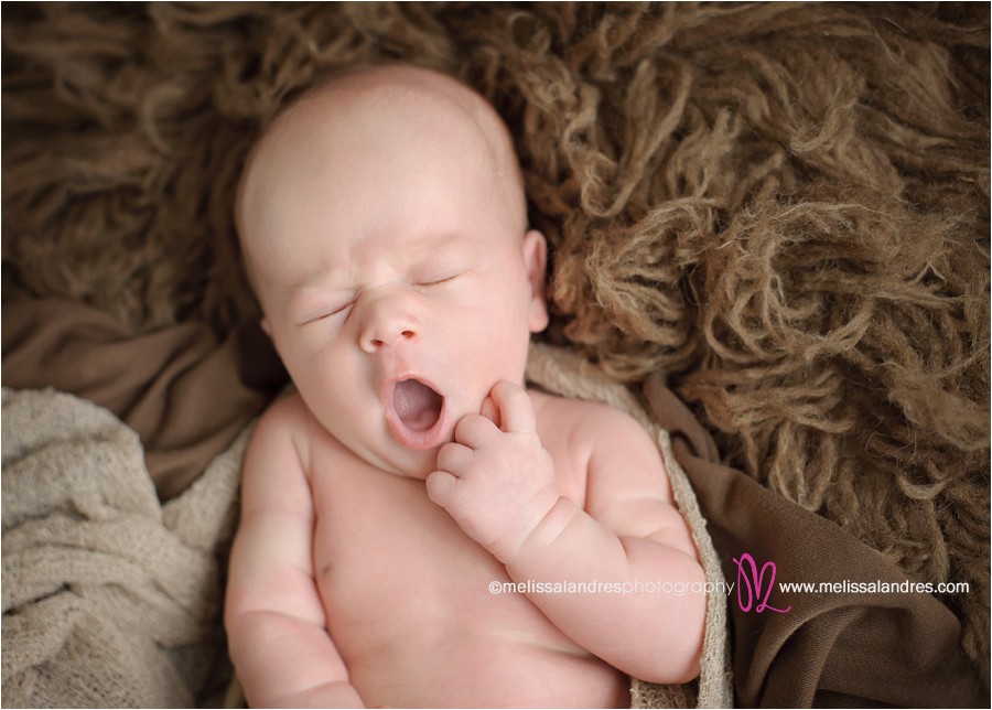 adorable sleeping yawning newborn baby boy on furry blanket prop